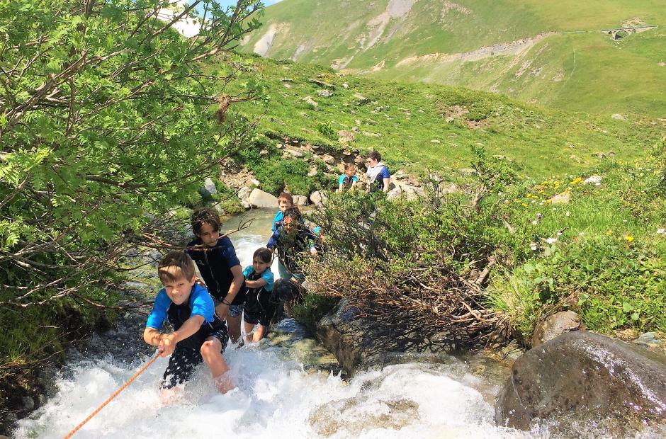 Des enfants remontant un cours d'eau à Saint-Sorlin-d’Arves grâce à une corde.
