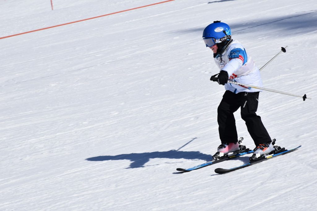 Jeune skieur qui descend les pistes en position de base.