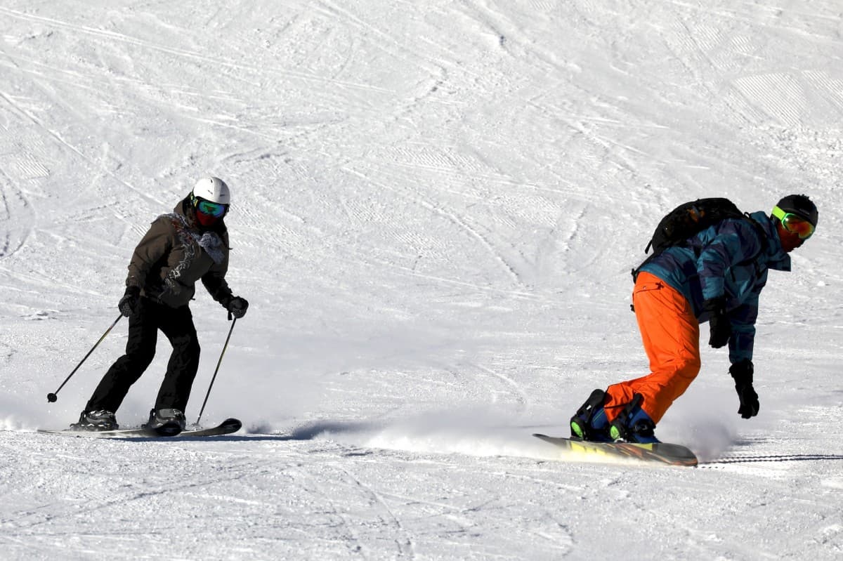 Un skieur et un snowboardeur en train de descendre une piste