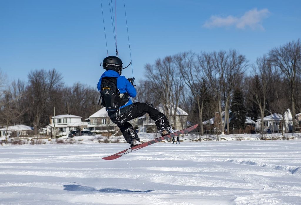 Un homme est photographié de dos en train de faire un saut en snowkite