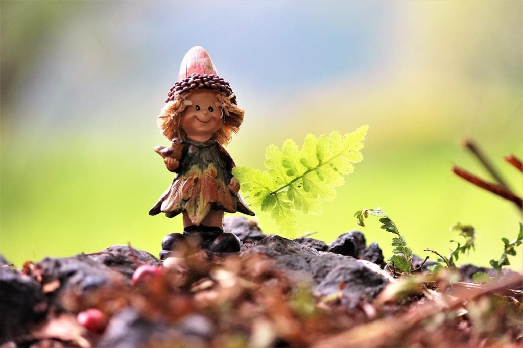 Un mini elf en bois posé dans une forêt.